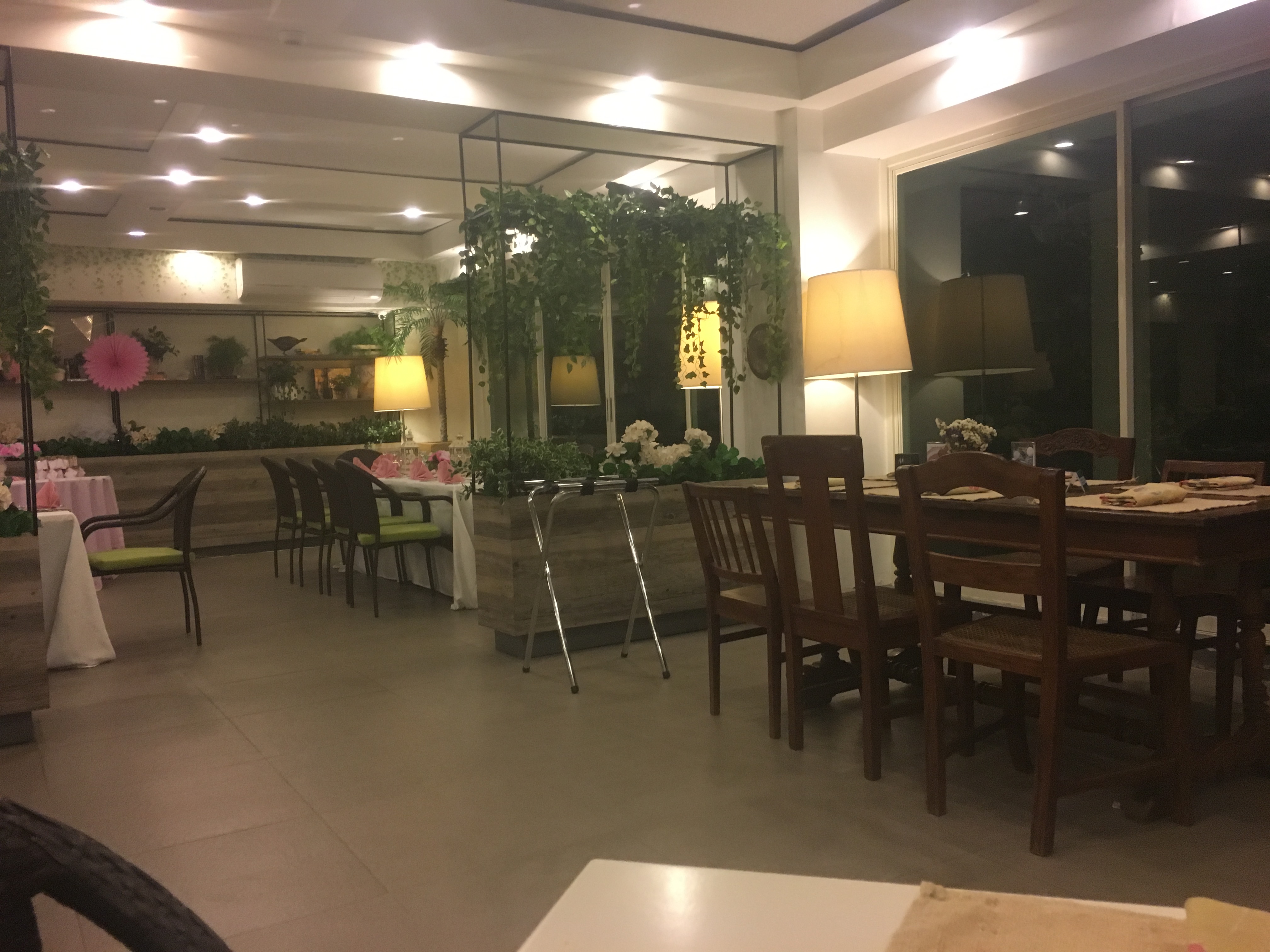 Happy Garden Cafe interior dining area with lush greenery, hanging vines, and warm lighting