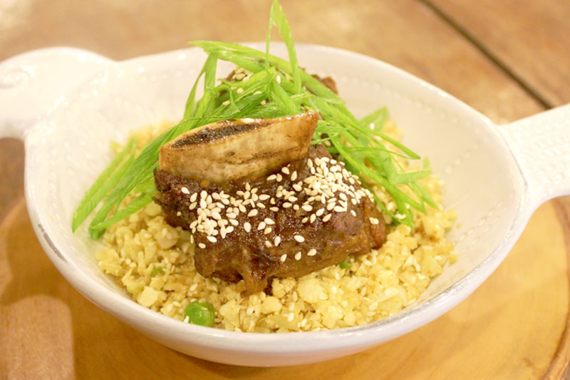 Cauliflower rice bowl with sesame-glazed meat and fresh scallions at Happy Garden Cafe